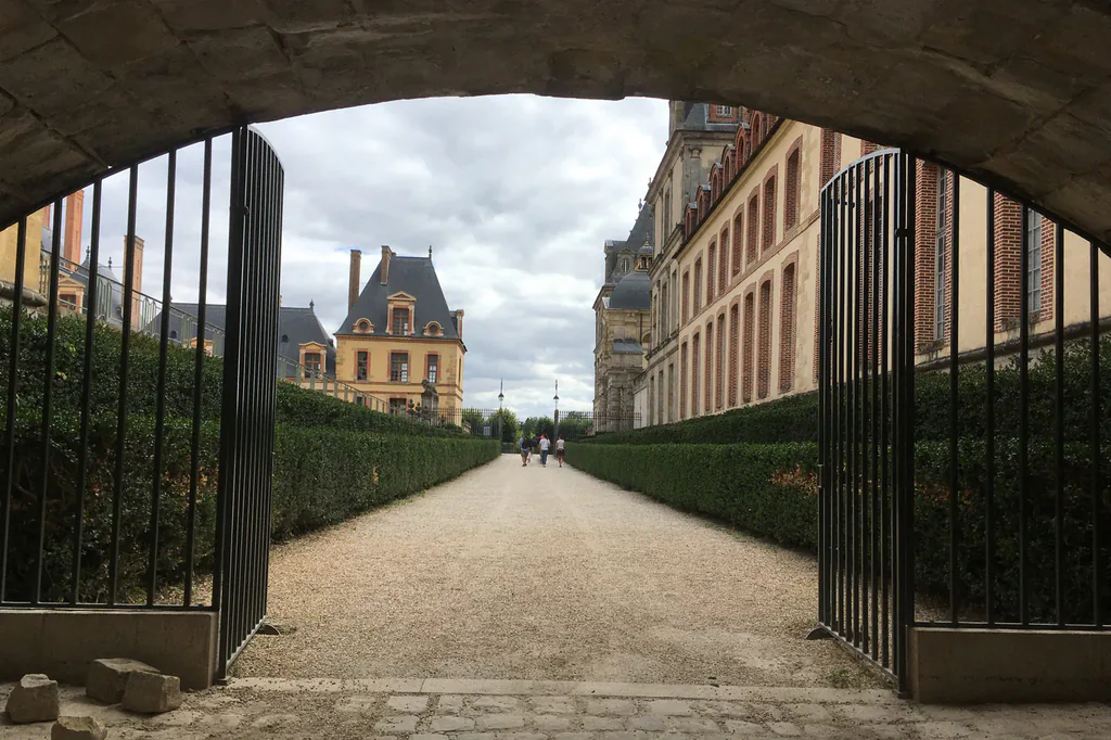Avant retouche : allée d’un château vue à travers une grille ouverte