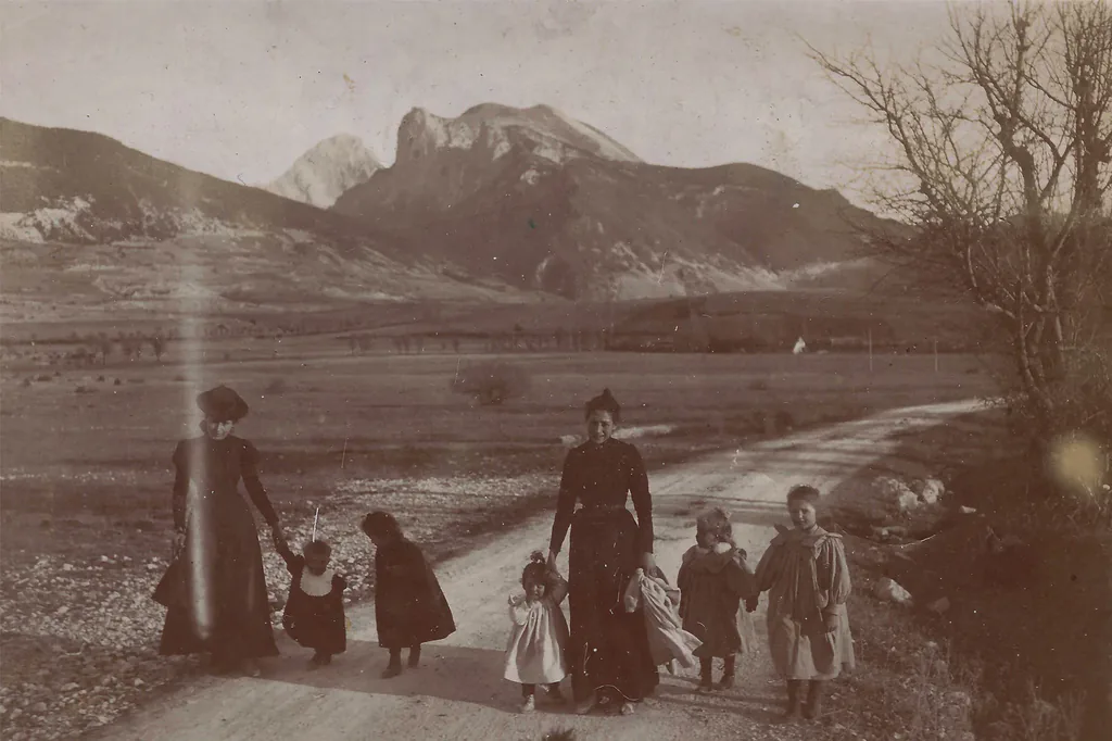 Avant restauration : famille en promenade sur un chemin de montagne, photo ancienne sépia abîmée