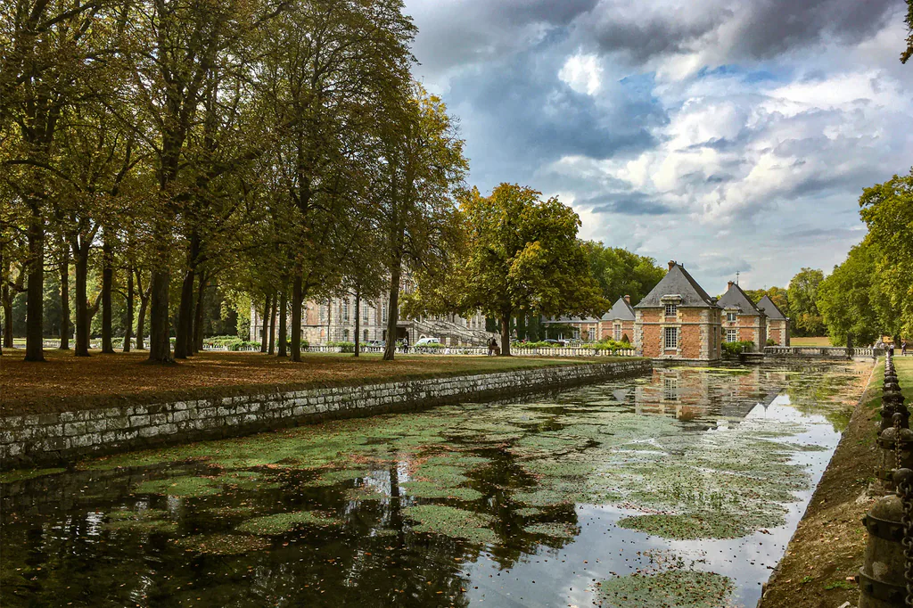Canal bordé d’arbres et ciel nuageux