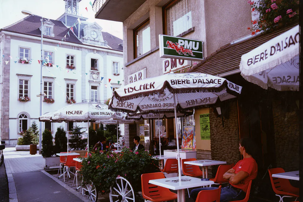Avant retouche : terrasse de café avec parasols et chaises rouges